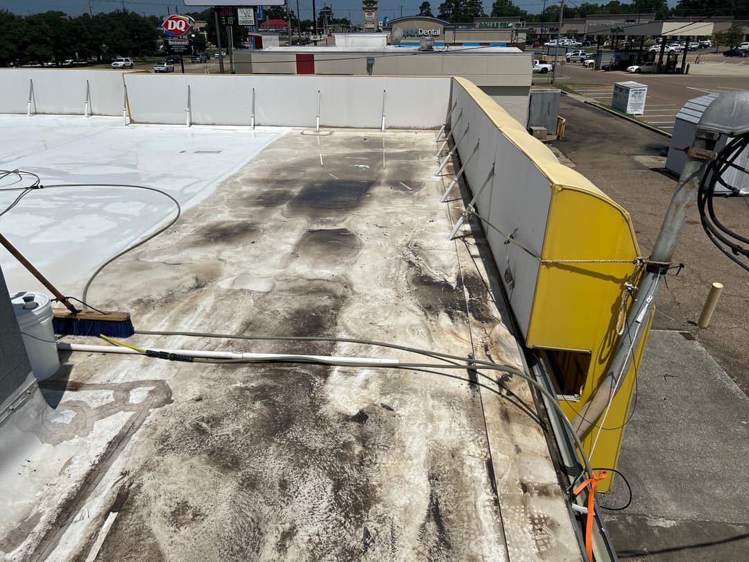 Roof of a commercial building showing debris, stains, and utility wires.