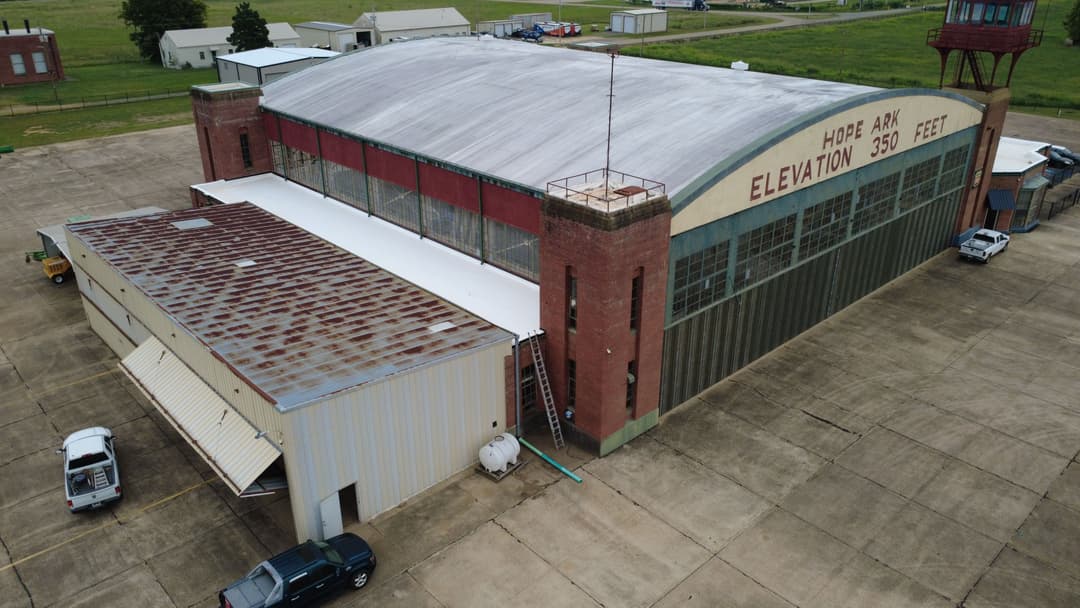 Hope Ark hangar building exterior with large glass windows and metal roof, overlooking rural landscape.
