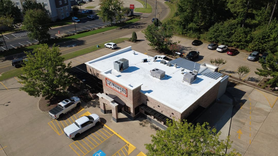 Aerial view of a restaurant building with a white roof and surrounding parking lot.