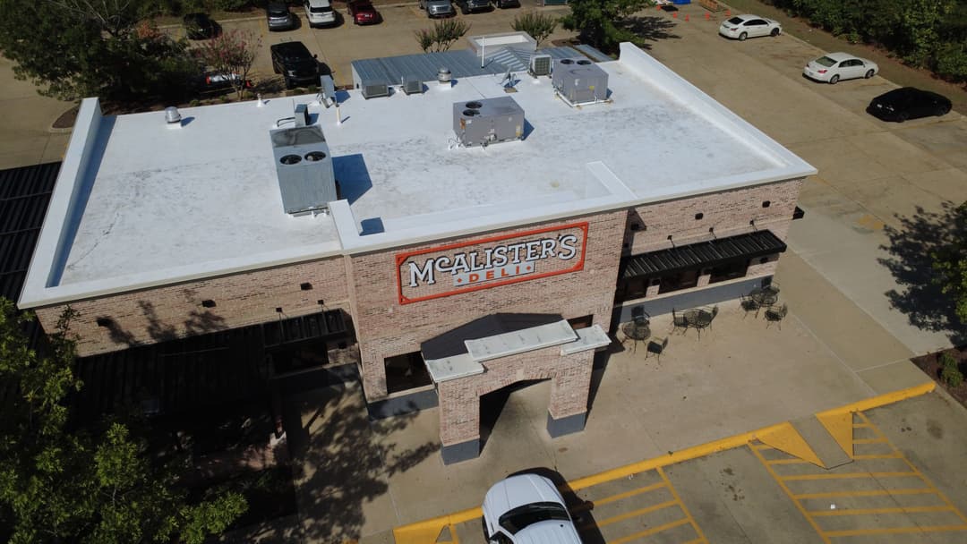 Aerial view of McAlister's Deli with parking lot and outdoor seating area.