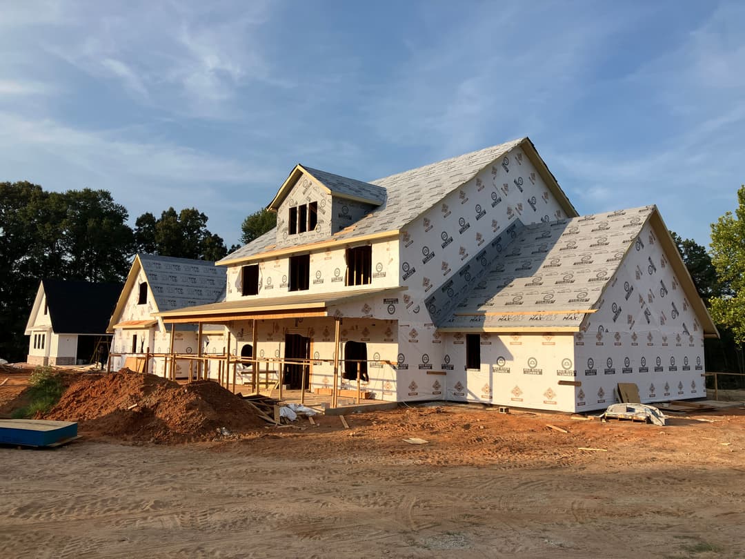 Newly constructed house with siding and roof under development at a building site.