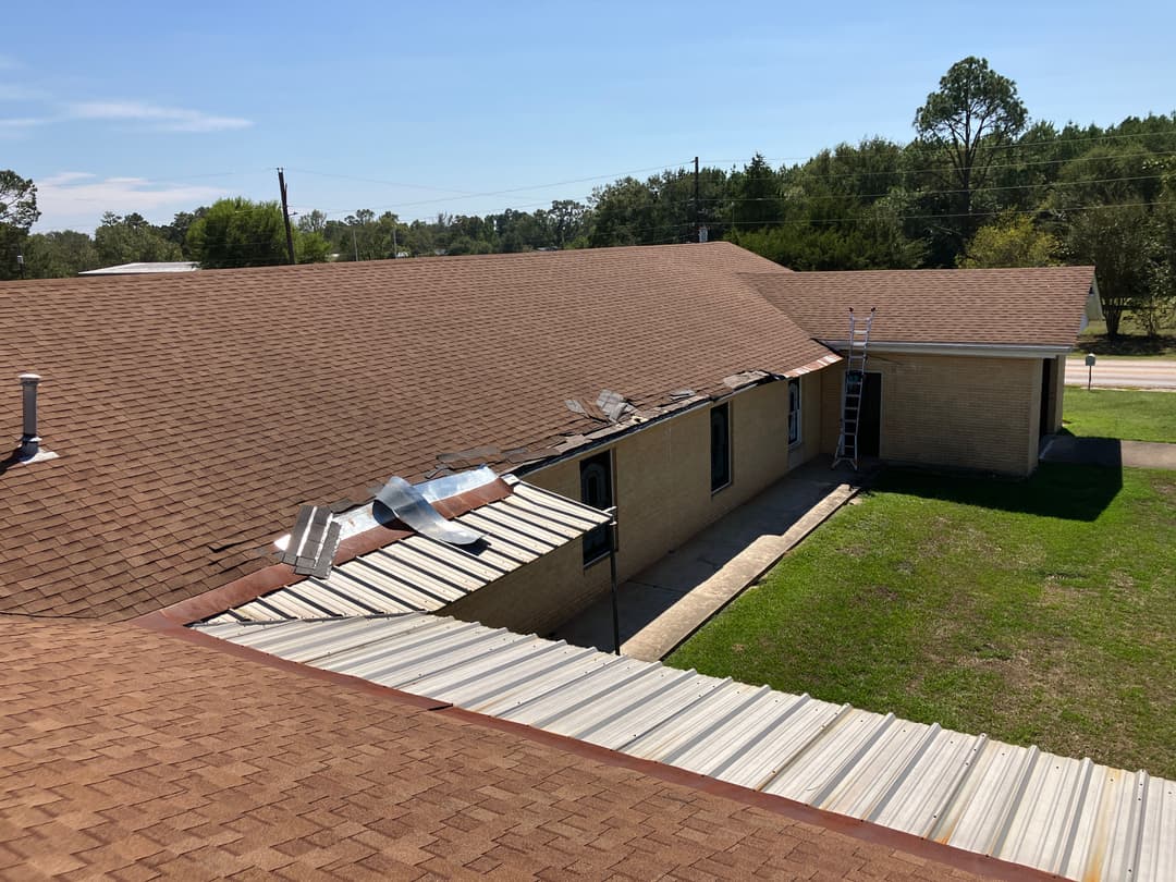 Roof renovation in progress on a building with ladders and materials visible.