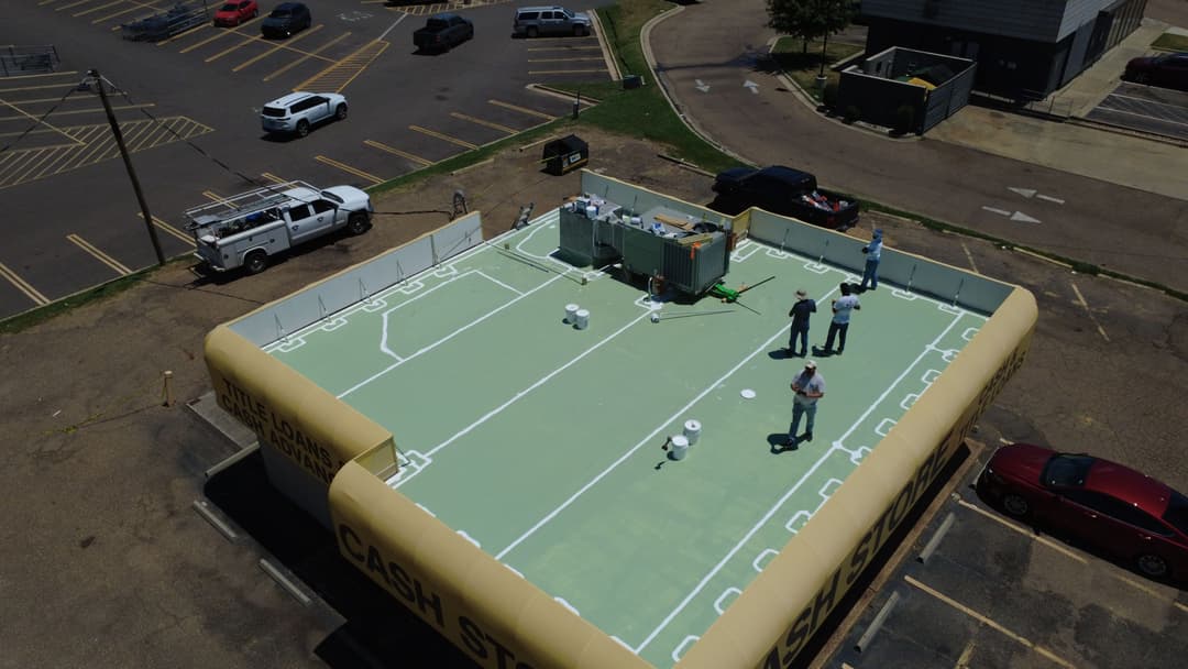 Aerial view of a cash storage facility with workers on a rooftop, featuring a unique inflatable design.